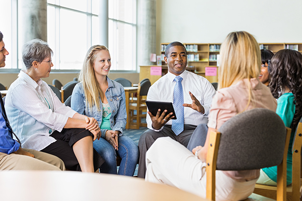 Man leading discussion group of adults and teens