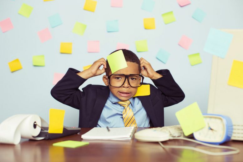 Young Businessman at Desk Covered with Blank Sticky Notes