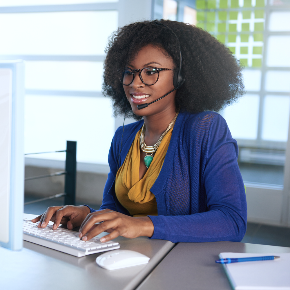 Woman typing on a computer and wearing a headset