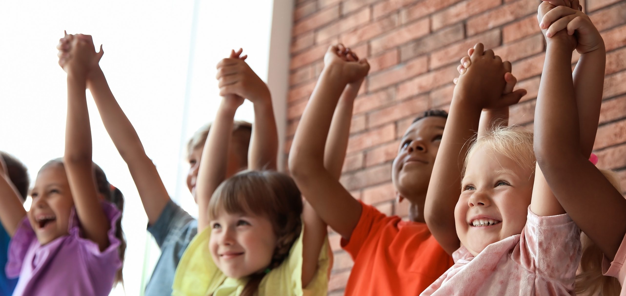 Group of children with their arms up holding hands