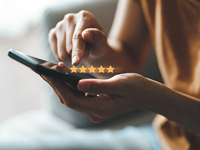 Adult typing five star review on smartphone