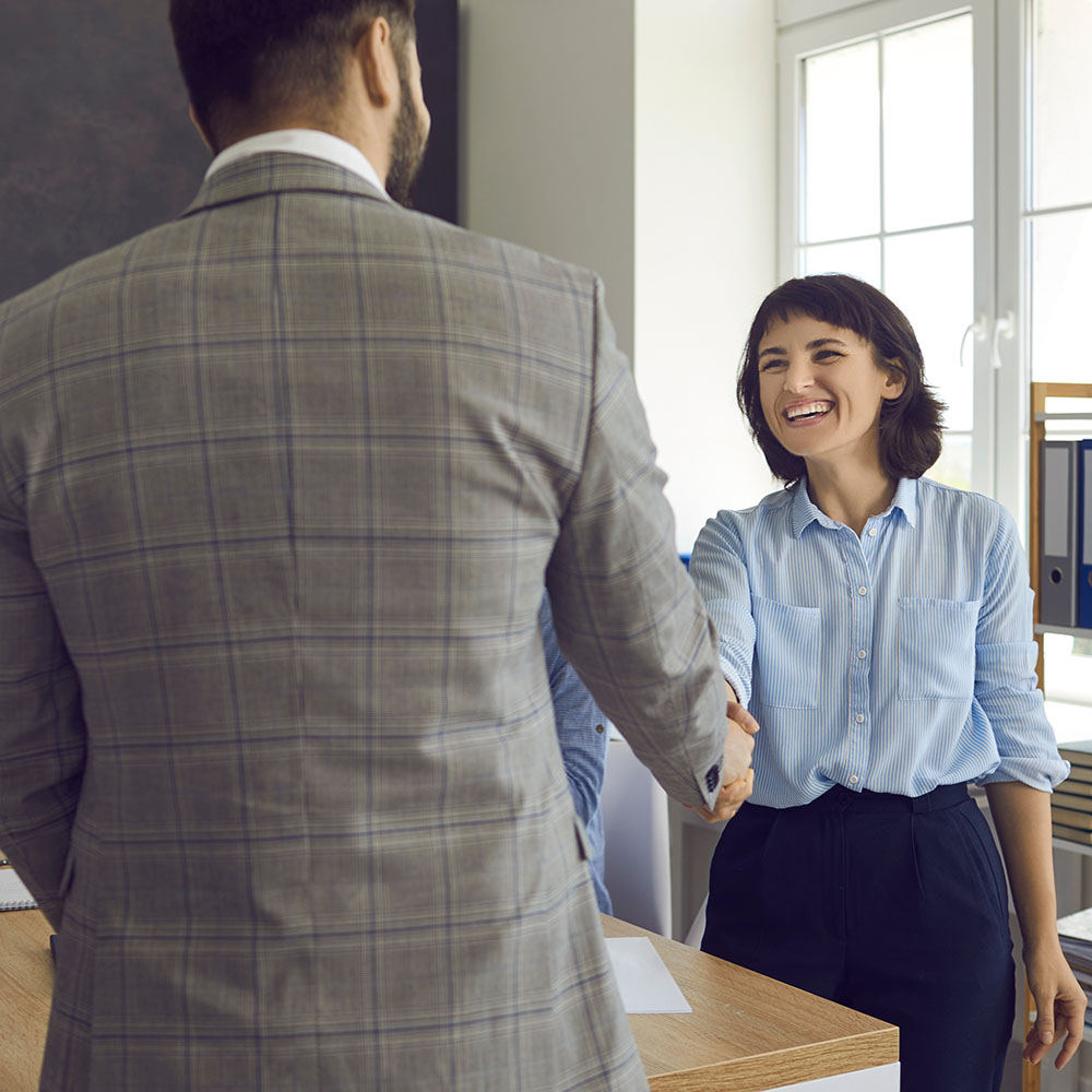 Business man and woman happily shaking hands in an office