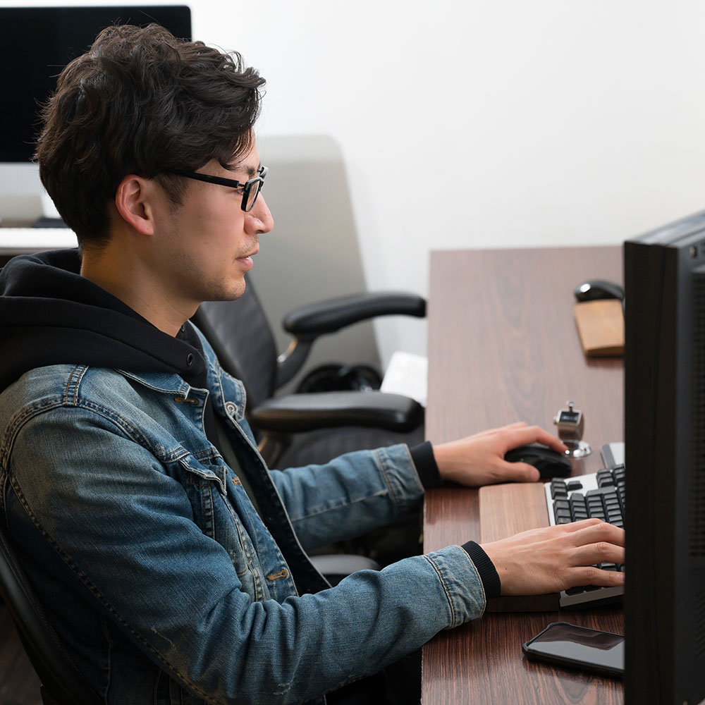 Casually dressed man with glasses typing on a computer in a computer room