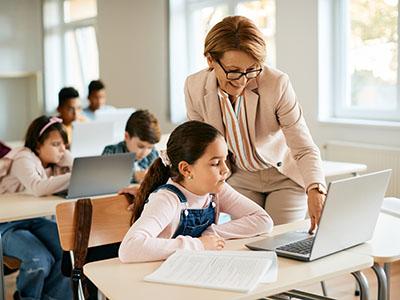 Teacher pointing to a young student's laptop screen