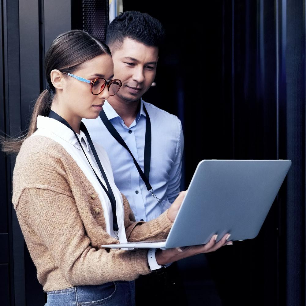 Business man and woman standing looking at laptop screen