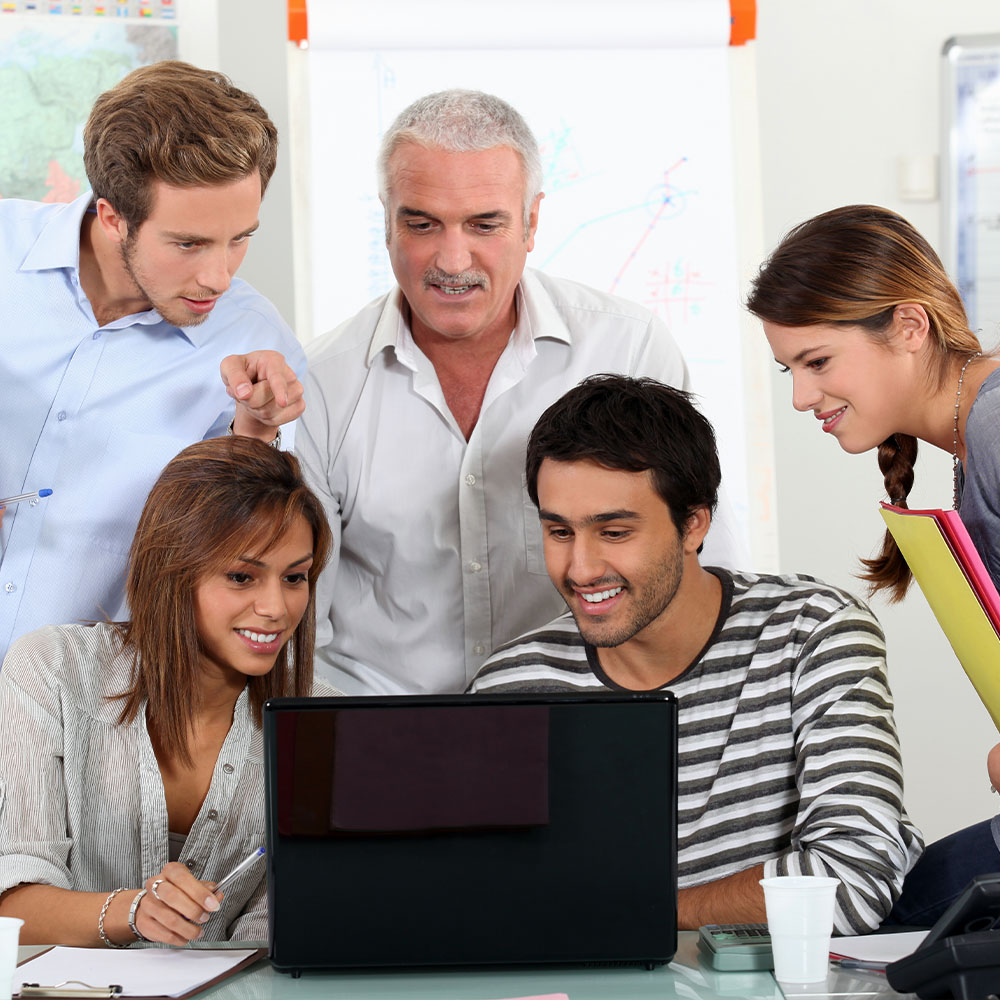 Five adults talking and looking at laptop screen