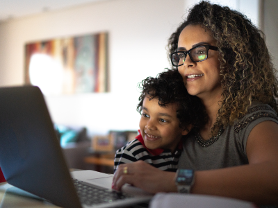 Mother and young son embracing and looking at laptop screen