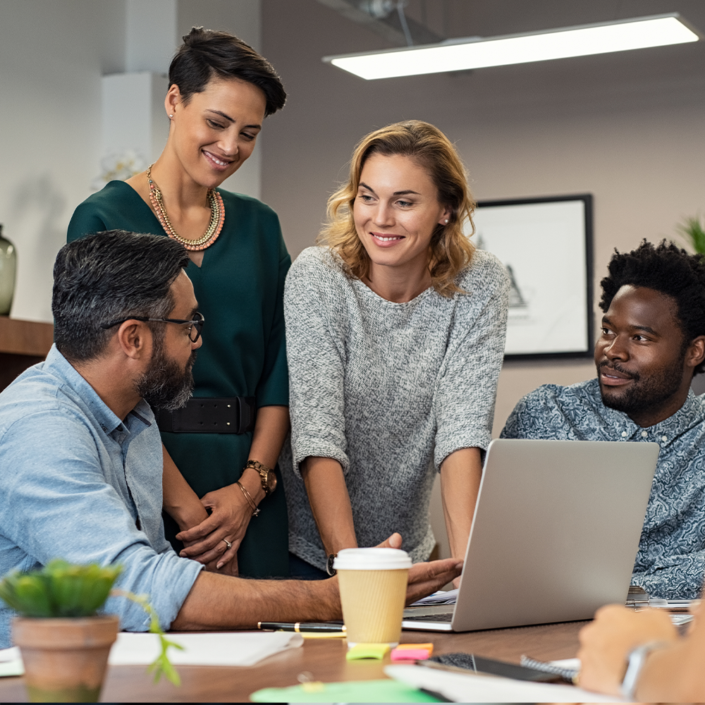 Four adults surrounding a laptop talking