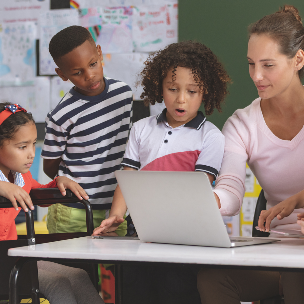 Teacher helping group of diverse students with laptop work