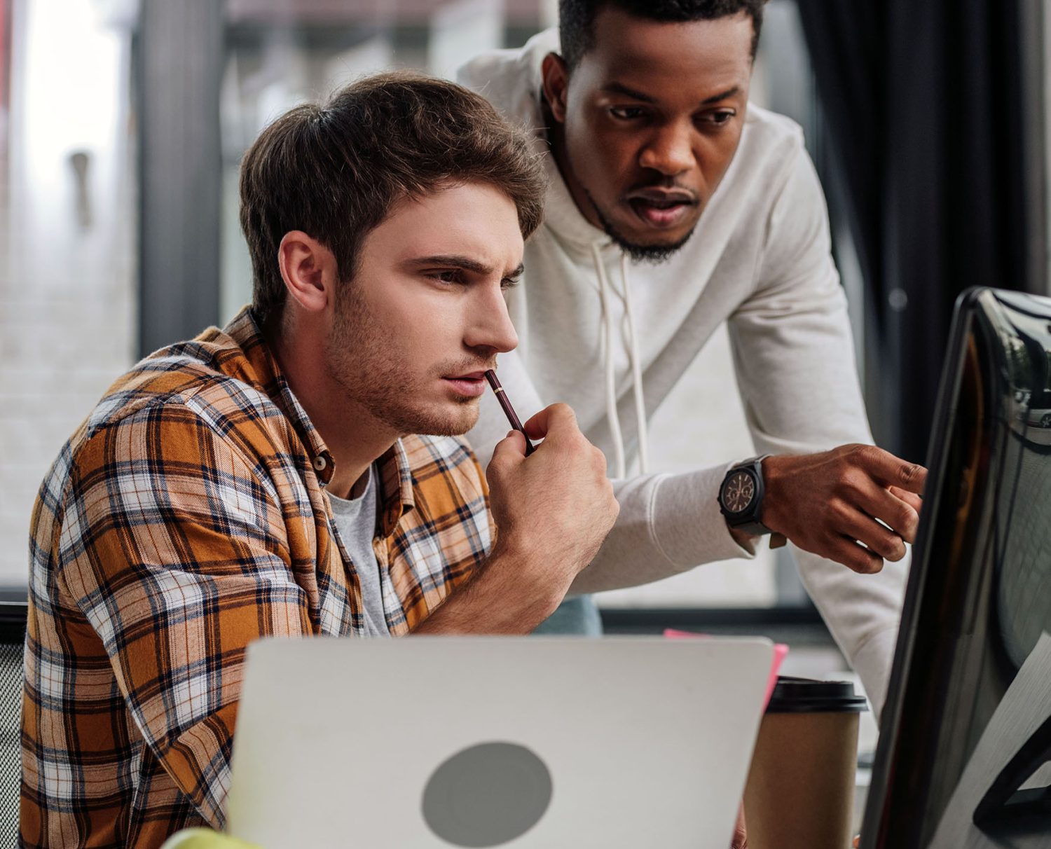 programmer pointing at computer monitor near colleague