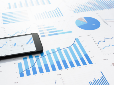 iPhone with graphs on its screen placed on top of a table with graphs and charts