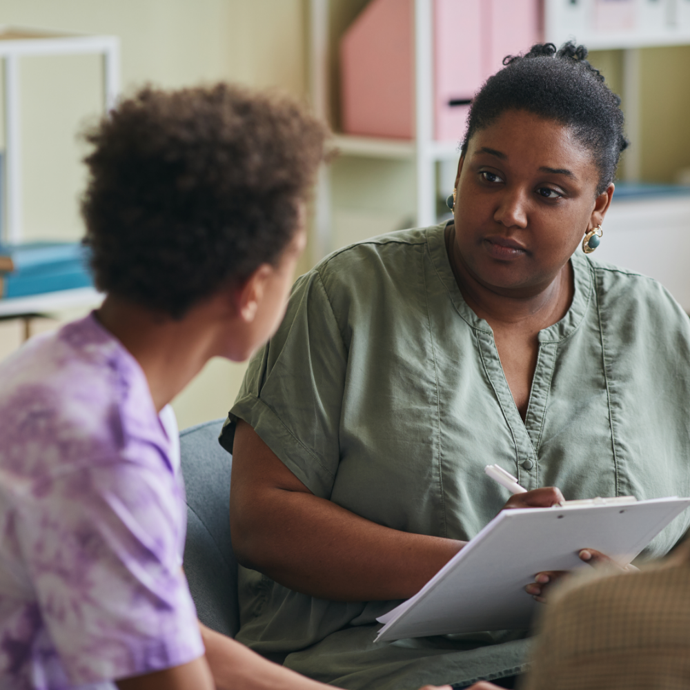 Woman with pen and paper in her hand talking with child