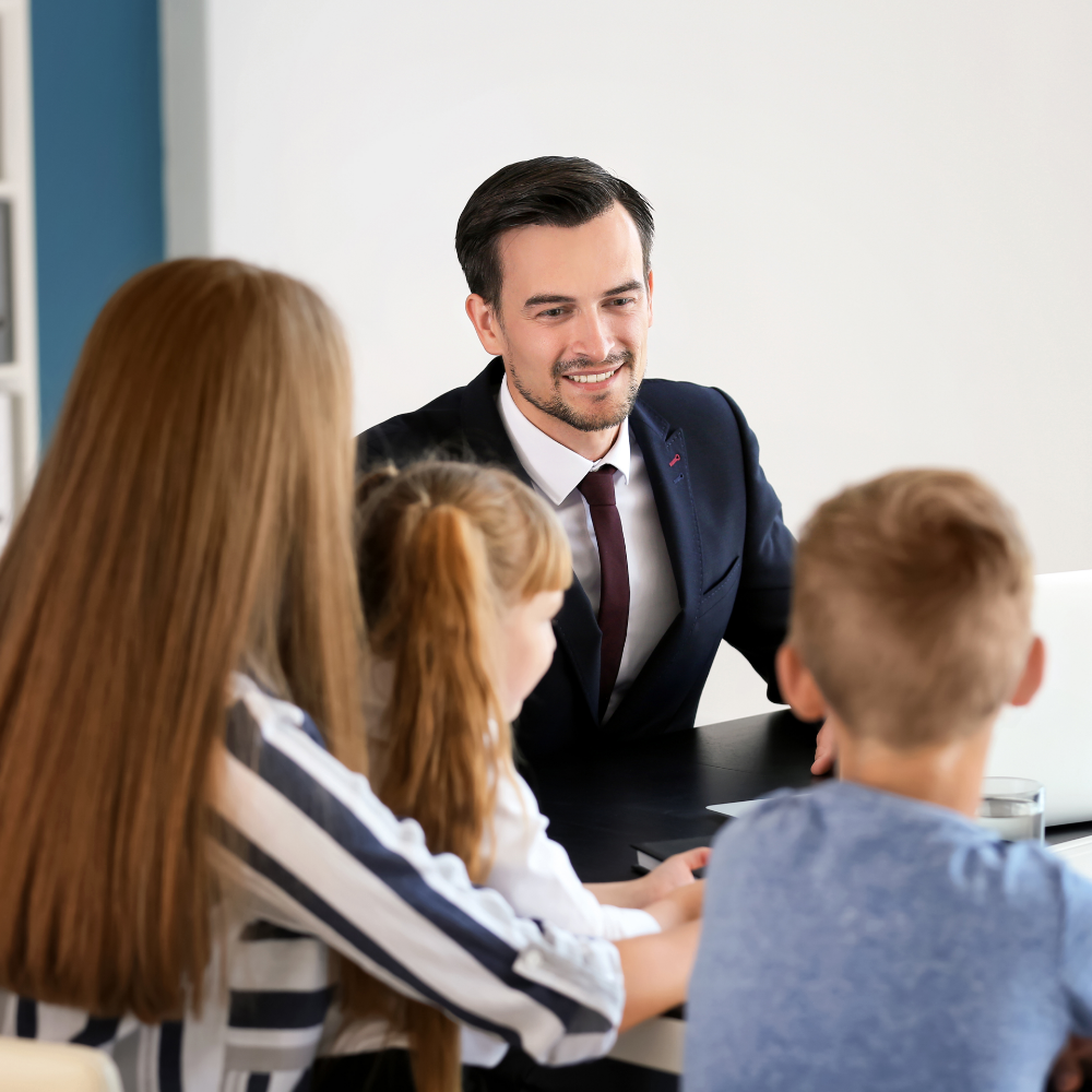 Business man in a suit talking to a mother and her two children in an office room