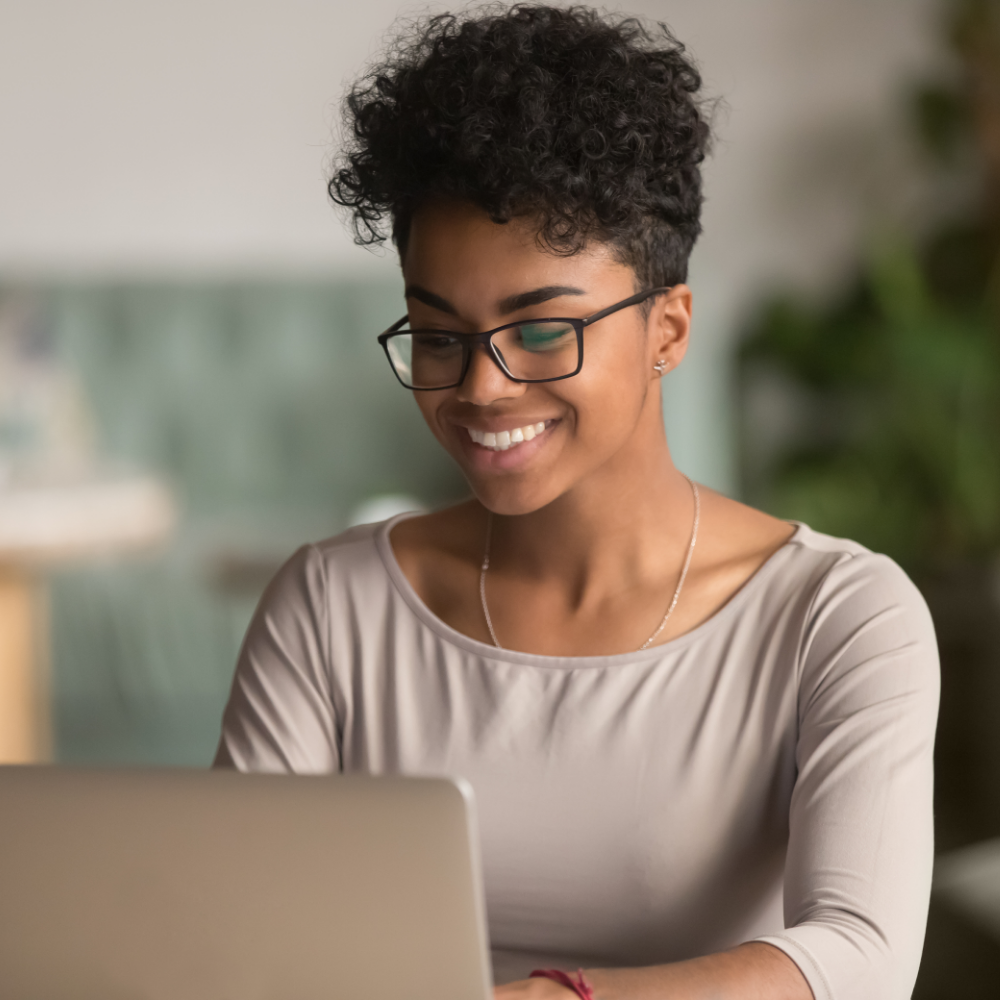 Woman wearing glasses smiling at her laptop