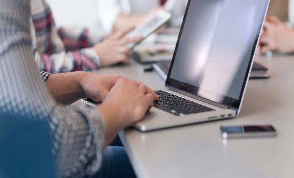 Close up of businessman hands typing on laptop during team meeting