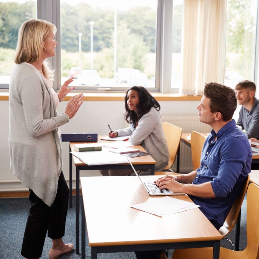 Female teacher actively teaching her diverse class as they pay close attention