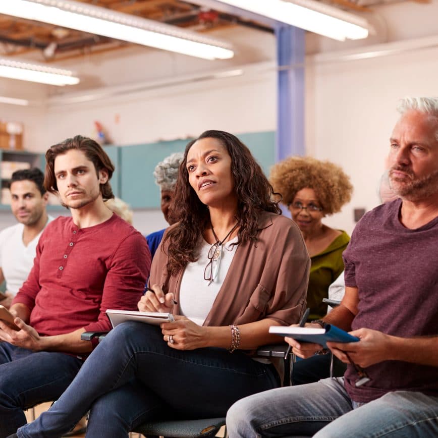 Group of adults taking notes while listening inventively