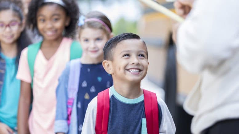 Excited young boy waiting in line after getting off the bus